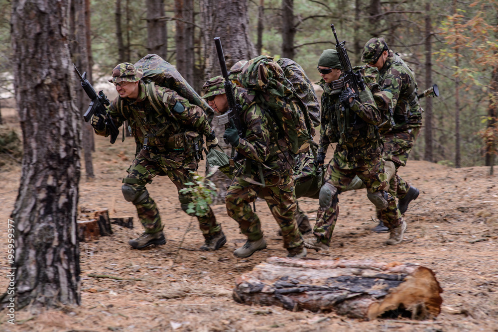Team of soldiers evacuate wounded soldier on a stretcher from battlefield in forest Team of soldiers evacuate wounded soldier on a stretcher from battlefield in forest