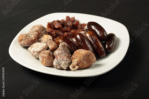 white plate with dried figs, dates and raisins