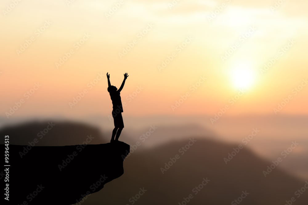 Silhouette of man standing on the cliff lift. Orange sky background