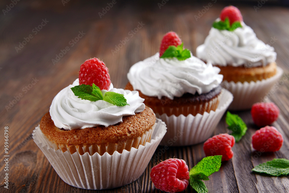 Delicious cupcakes with berries and fresh mint on wooden table close up