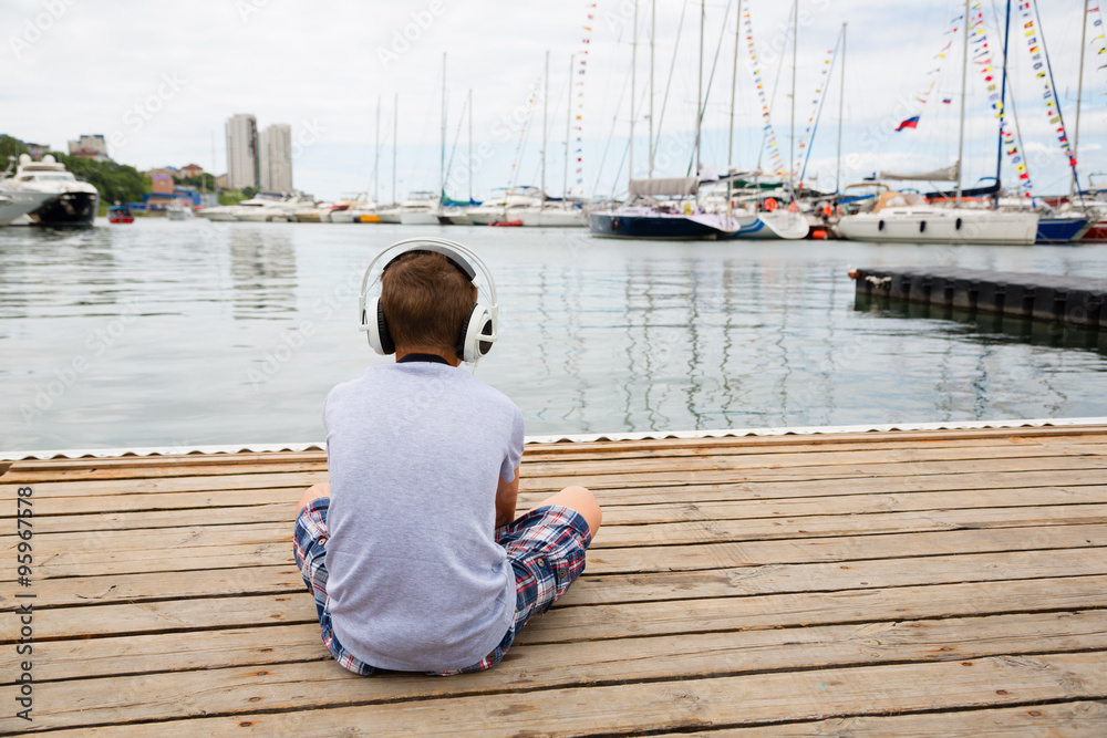 Boy with headphones sitting on the mooring