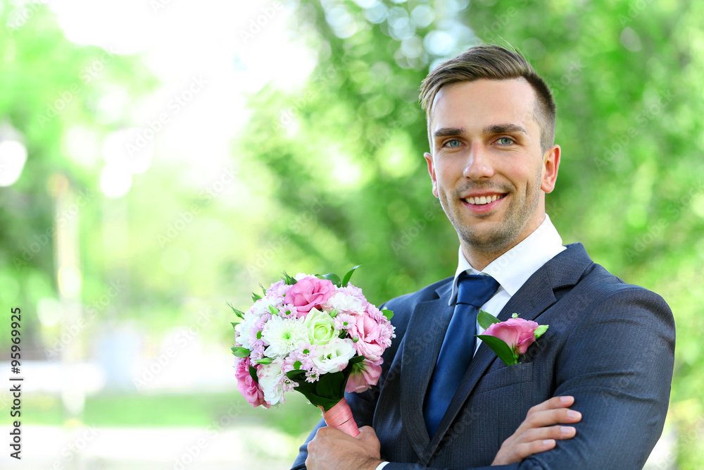 Groom holding wedding bouquet outdoors Groom holding wedding bouquet outdoors