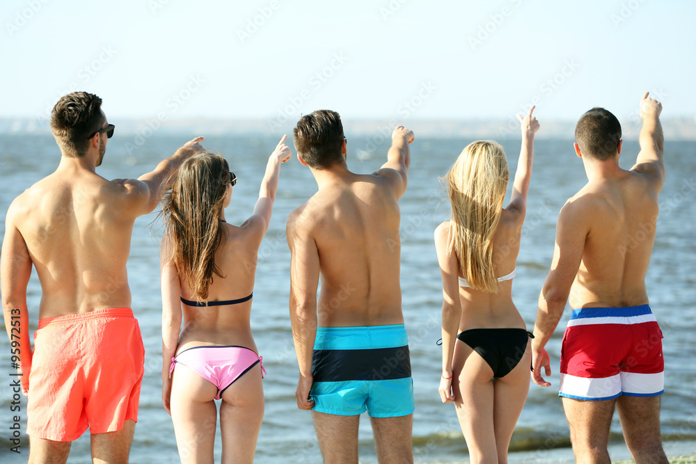 Back view of friends standing at the beach, outdoors Back view of friends standing at the beach, outdoors