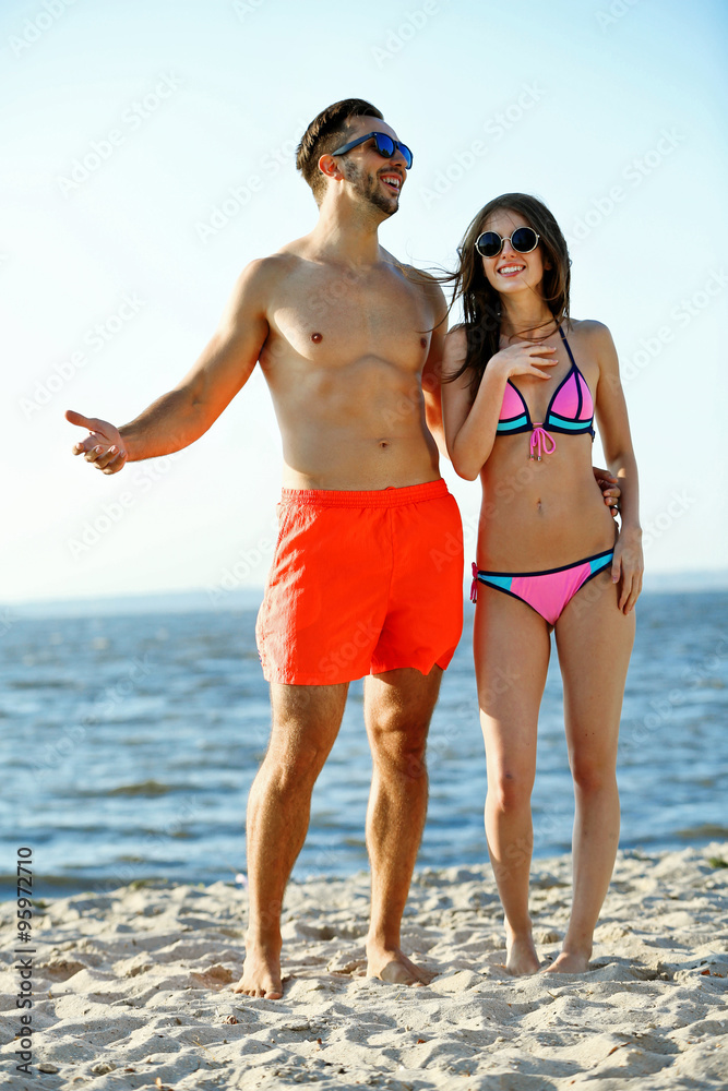 A guy hugging a girl at the beach, outdoors