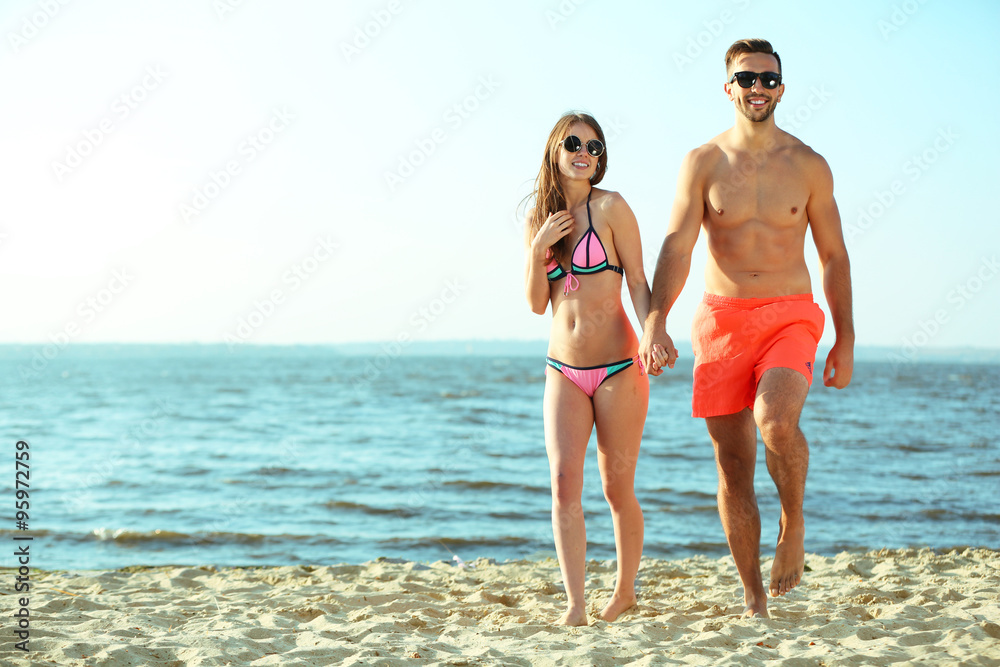 A happy couple holding hands at the beach, outdoors