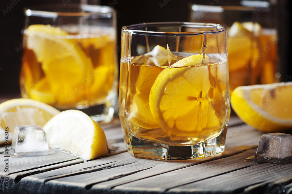 Cold whiskey with ice and lemon on the vintage table Cold whiskey with ice and lemon on the vintage table