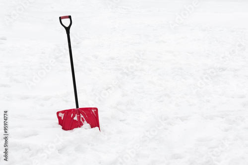 Red snow shovel standing in snow.
