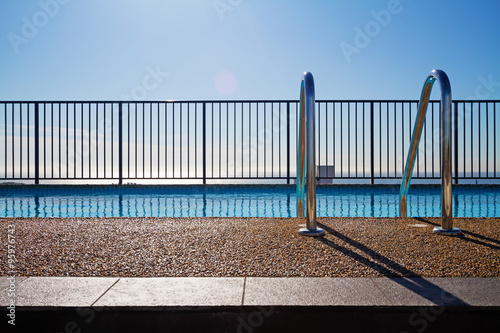 Swimming pool edge with ladder and sky background