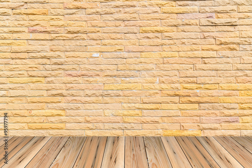 Orange brick wall as a nicely textured background on wood floor.