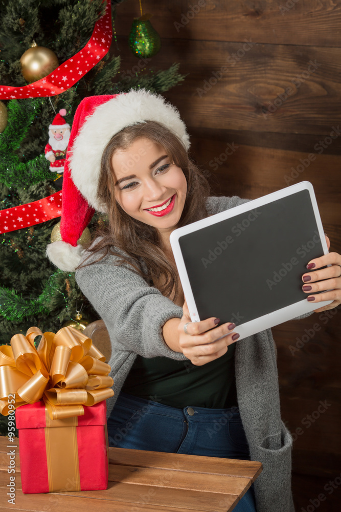 Beautiful girl making selfies on tablet PC near New Year tree Beautiful girl making selfies on tablet PC near New Year tree