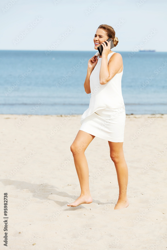 Young elegant beautiful woman talking on the phone on the beach Young elegant beautiful woman talking on the phone on the beach