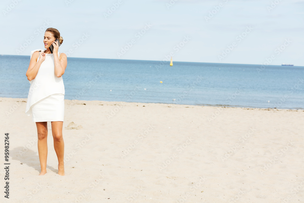 Young elegant beautiful woman talking on the phone on the beach Young elegant beautiful woman talking on the phone on the beach
