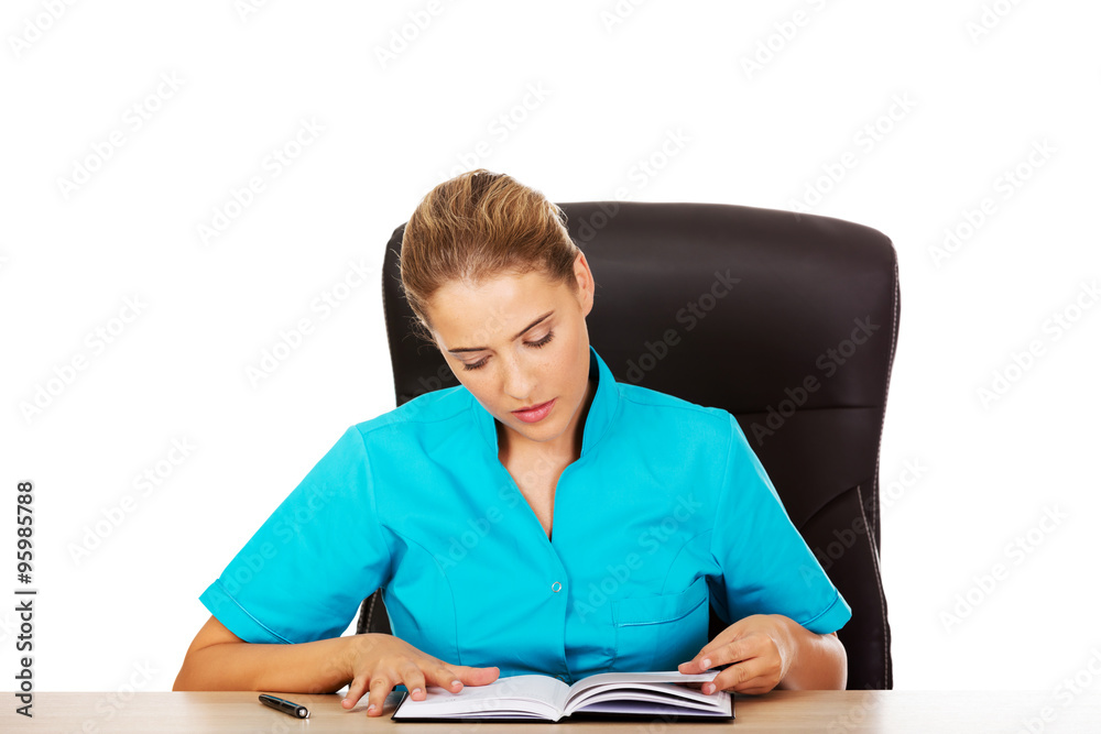 Female doctor sitting behind the desk and writing a notes Female doctor sitting behind the desk and writing a notes