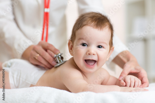 Tableau sur toile Pediatrician doctor examines baby with stethoscope checking heart beat