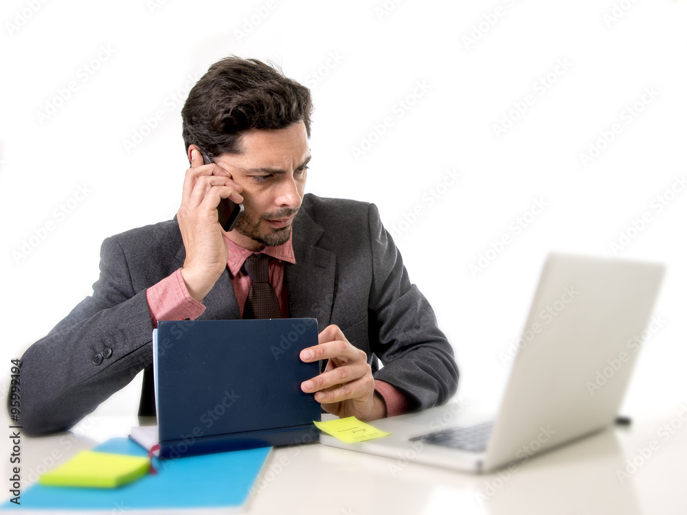 attractive businessman sitting at office desk working in stress on computer laptop talking on mobile phone overworked attractive businessman sitting at office desk working in stress on computer laptop talking on mobile phone overworked