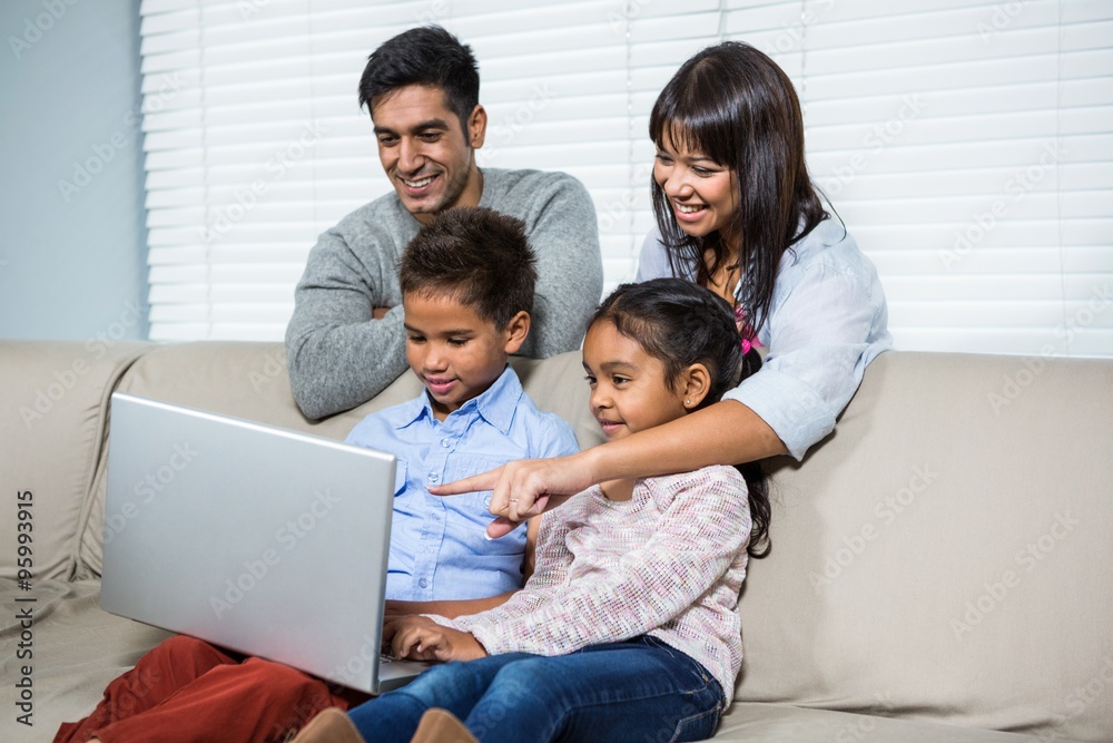 Smiling family using laptop on the sofa Smiling family using laptop on the sofa