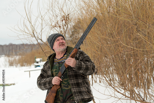 Hunter with a rifle in winter snow landscape