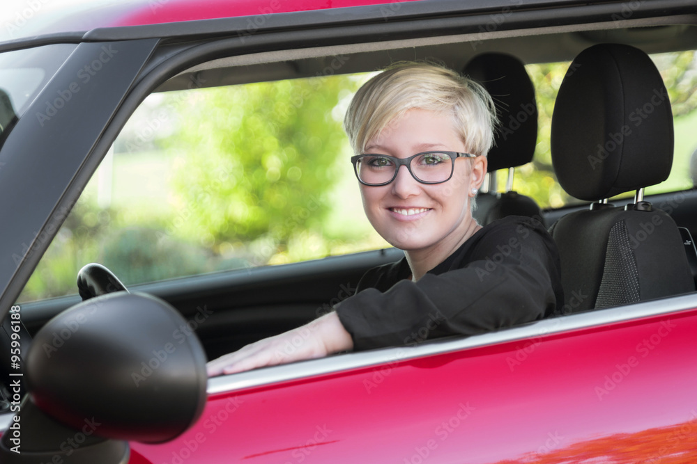 Young woman sitting proud in her car