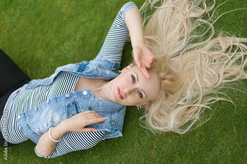 Blonde woman lying on the grass with untressed hair photo