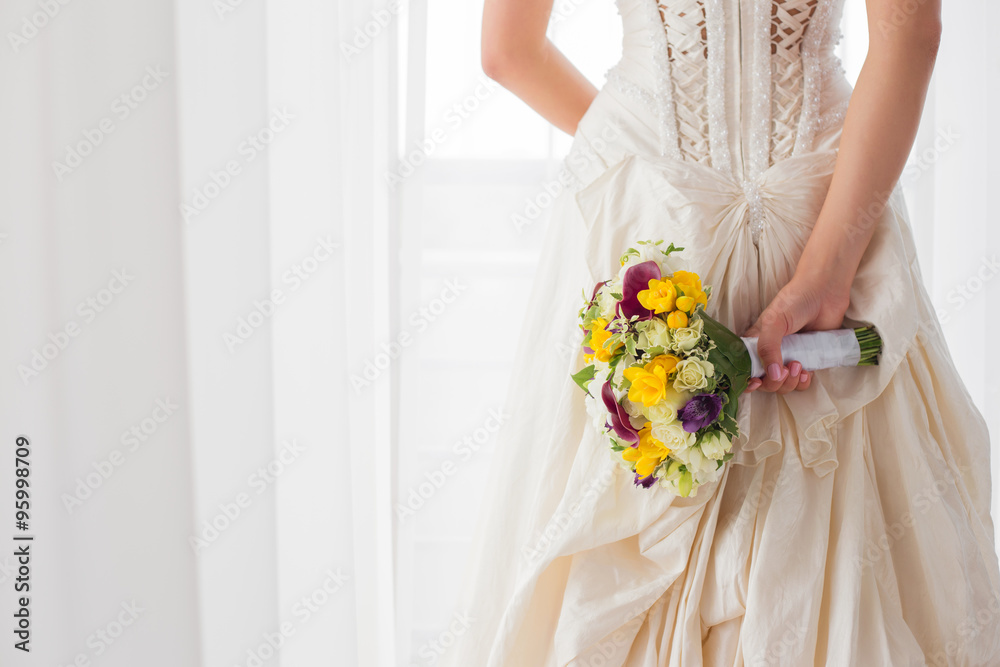Bride holding her wedding flowers behind her back - obrazy, fototapety, plakaty 