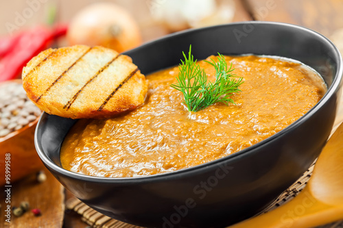 Bowl of lentil cream soup with toasts on kitchen table