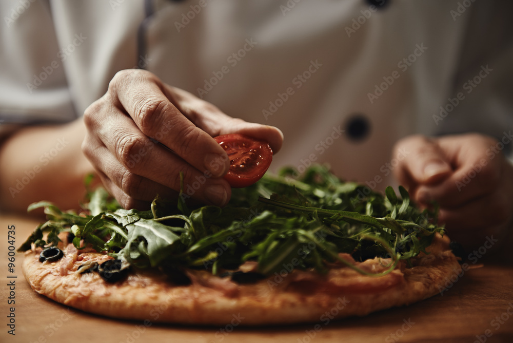 Female baker preparing pizza with ham, arugula and cherry tomatoes. Mediterranean cuisine. Female baker preparing pizza with ham, arugula and cherry tomatoes. Mediterranean cuisine.