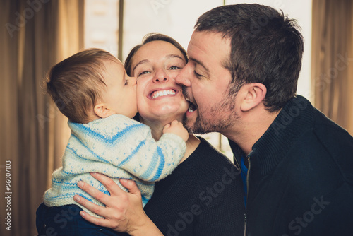 Beautiful young family. Father and son kissing the mother