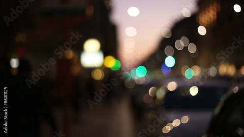 slow motion of people walking in the street at the sunset in a blurred and out of focus context in a big busy city with lights and colors photo