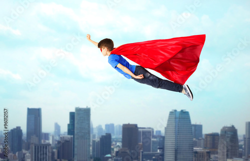 boy in red superhero cape and mask flying on air