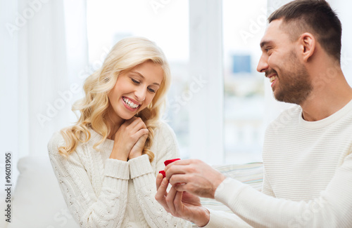 happy man giving engagement ring to woman at home