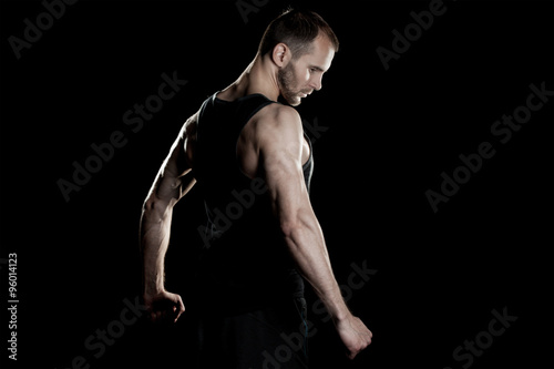 muscular man   clasps hands in  fist  black background  place for text on the right