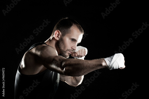 muscular man,strikes right, black background, horizontally