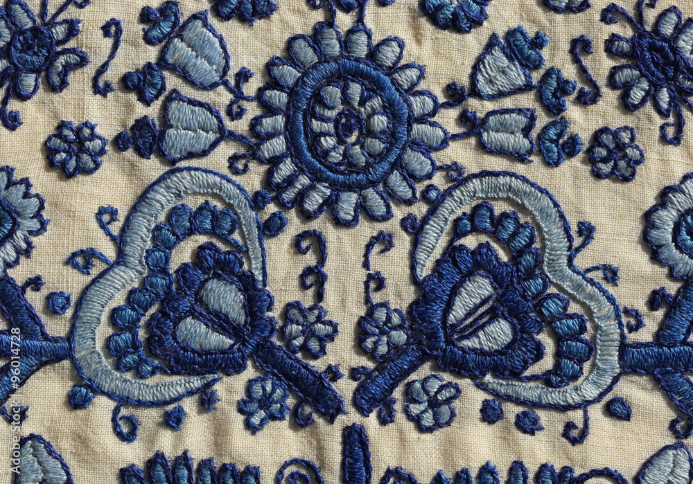 Embroidery background.
Vintage embroidery close-up with floral motif in blue shades on linen. 
