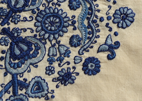 Embroidery background.
Vintage embroidery close-up with floral motif in blue shades on linen. 
