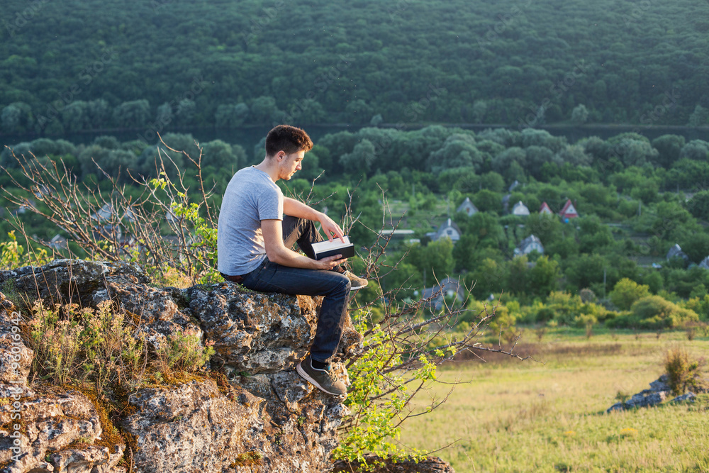 man sits on the edge of a cliff and reading a book