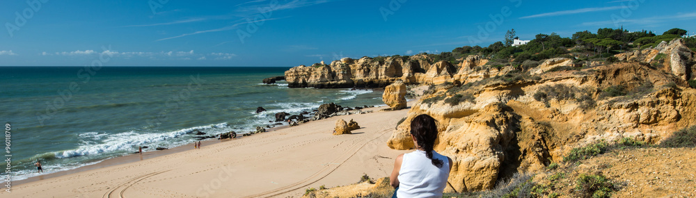 Woman is watching the ocean at Praia de Sao Rafael, Algarve, Portugal