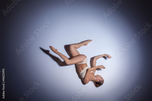 Young beautiful dancer in beige swimwear dancing on lilac background