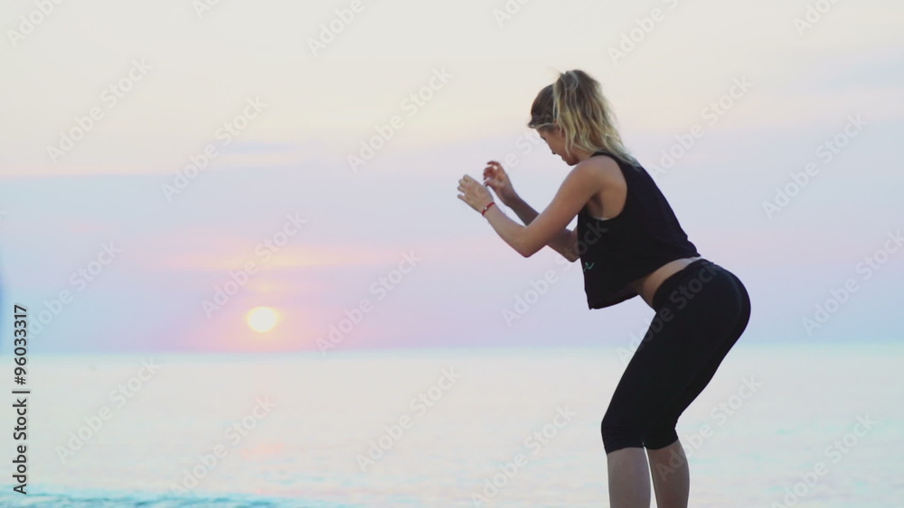 young female does squats on the beach slow motion