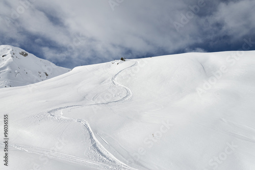 Winding snowboard trail among virgin snow mountains
