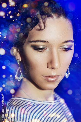 Young beautiful girl with a New Year s make-up on New Year s party. Portrait of a girl in blue lights. New Year s Eve 2016.