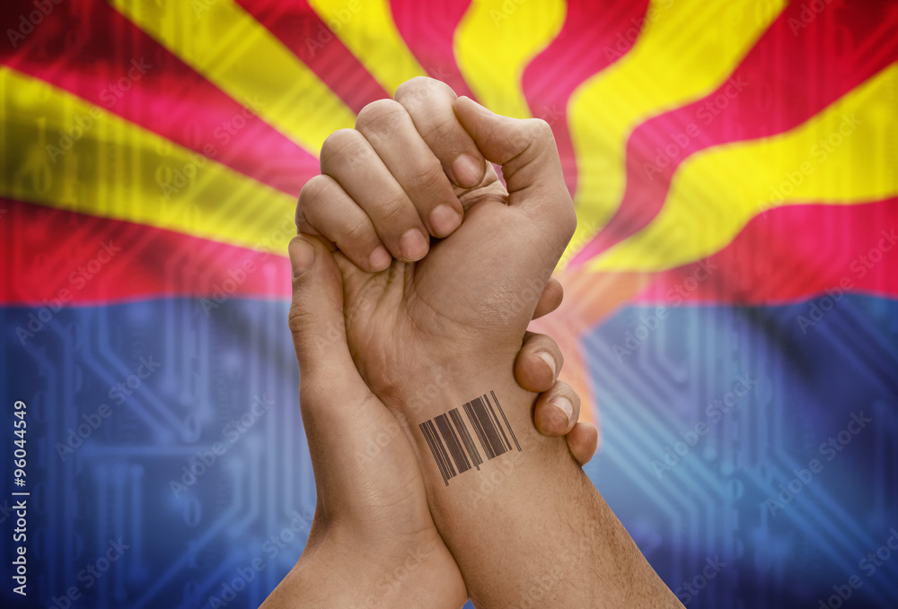 Barcode ID number on wrist of dark skinned person and USA states flags on background - Arizona