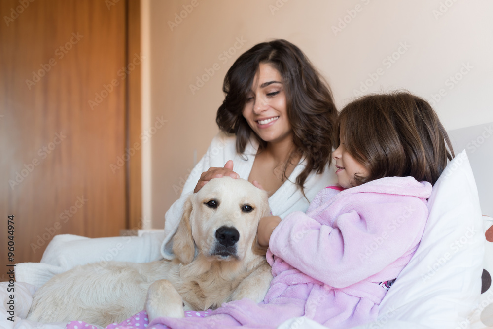 Mother and daughter with dog in bed