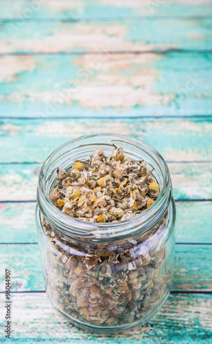 Dried charmomile herbal tea in mason jar over wooden background photo