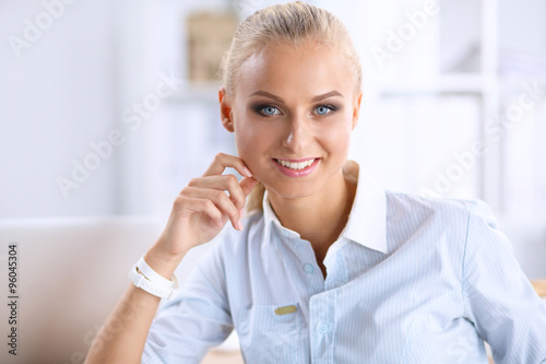 Attractive businesswoman sitting on a desk with laptop in the office