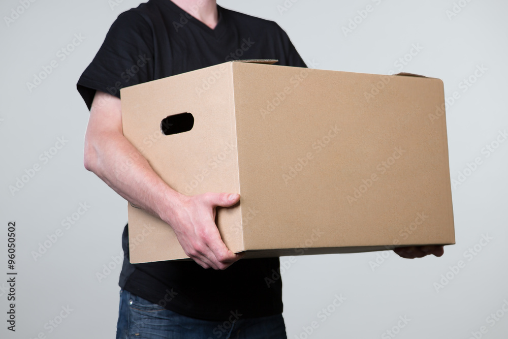 Ein Mann in schwarzem Shirt trägt einen schweres Paket zur Auslieferung  Stock Photo | Adobe Stock