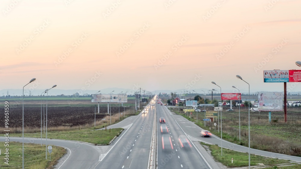 Speed Traffic At Sundown Time - Light Trails On Motorway Highway At Night Speed Traffic At Sundown Time - Light Trails On Motorway Highway At Night