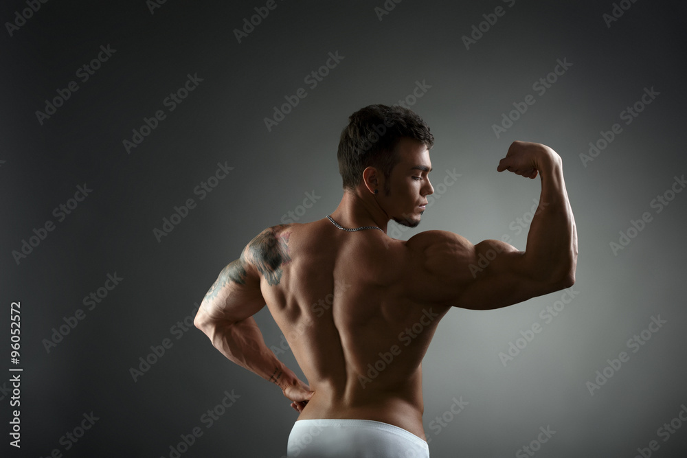 Rear view of tattooed bodybuilder showing biceps