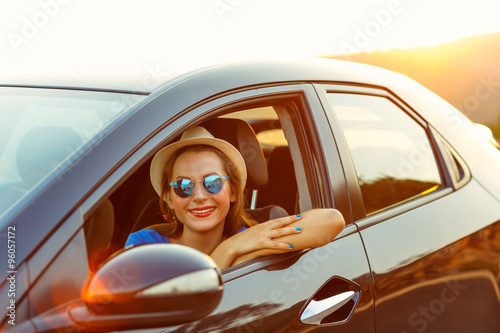 Smiling woman driving a car at sunset