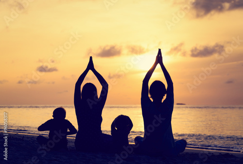 family silhouettes doing yoga at sunset