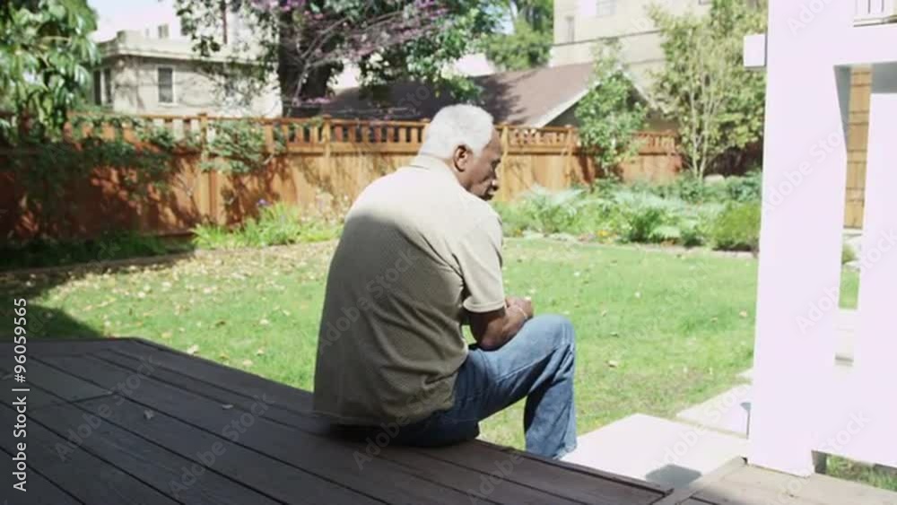 Senior black man sitting on porch outdoors thinking